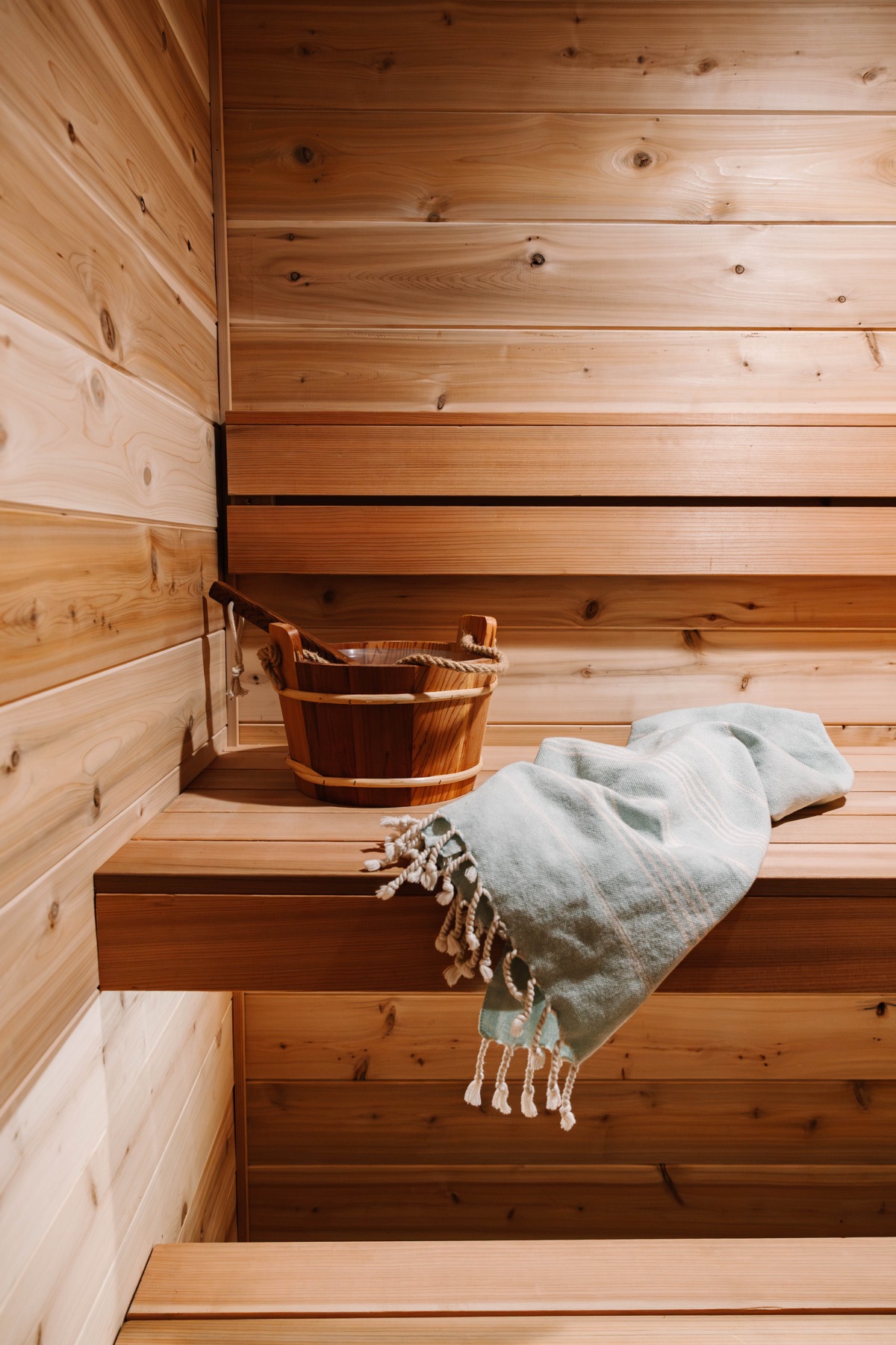 Cedar bucket, ladle, and towel on a sauna bench