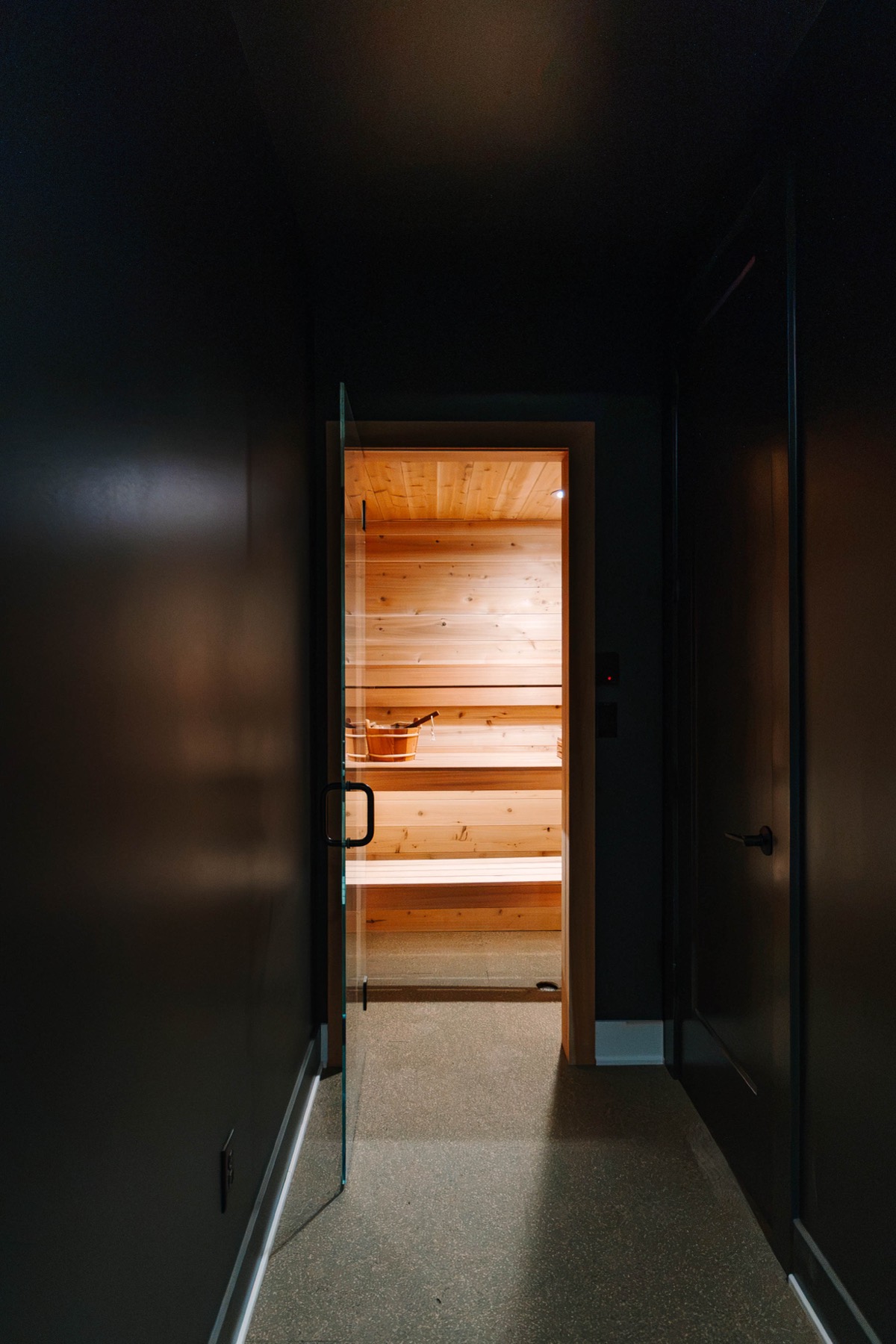 Dark hallway opening onto a glowing cedar sauna